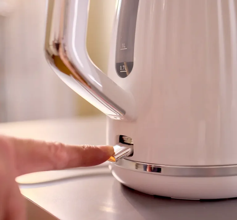 Finger pressing illuminated switch on electric kettle