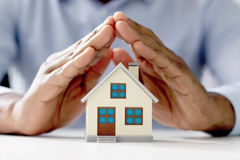Hands protect a miniature house model