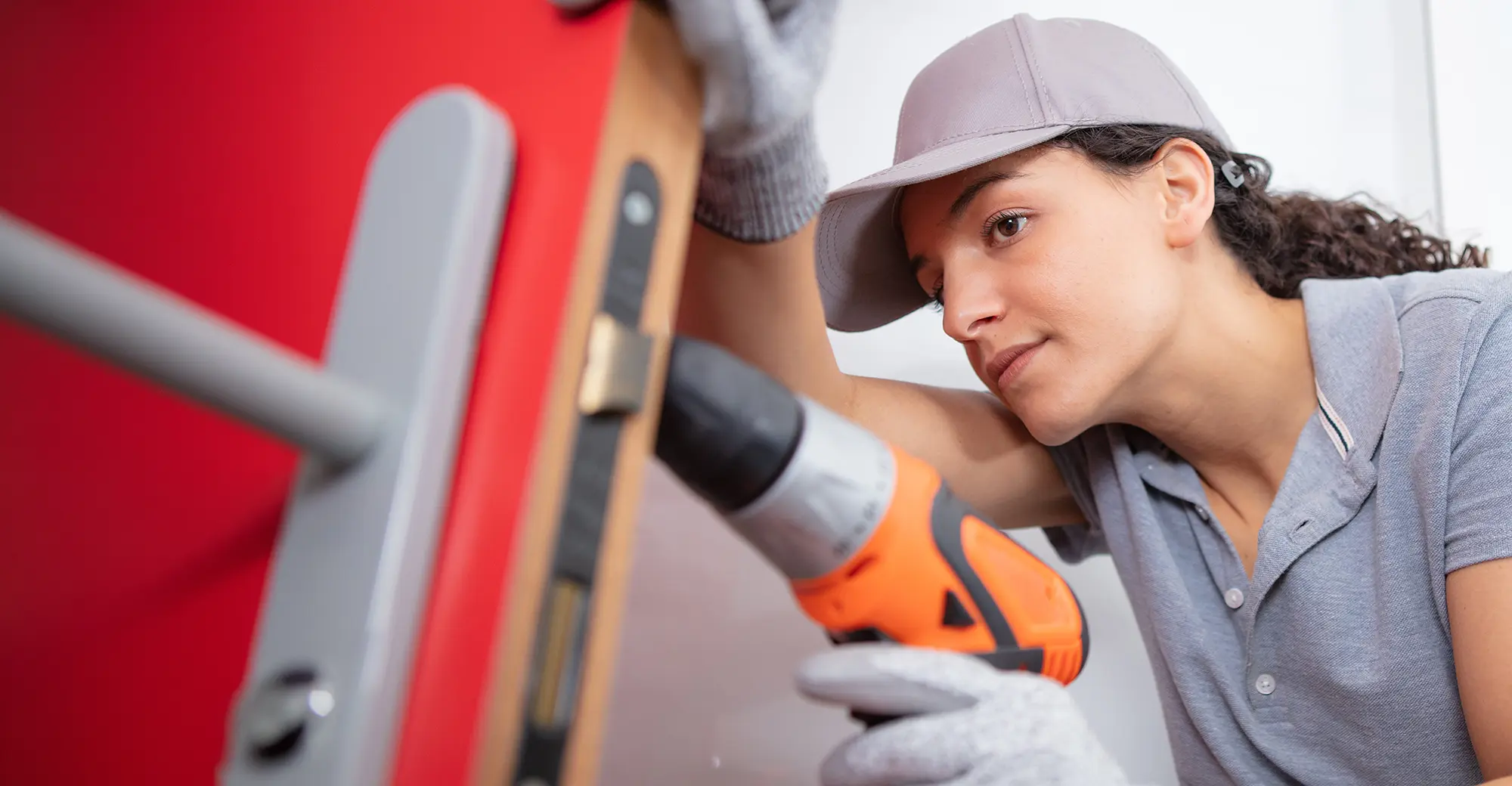 Female technician drilling a red door frame