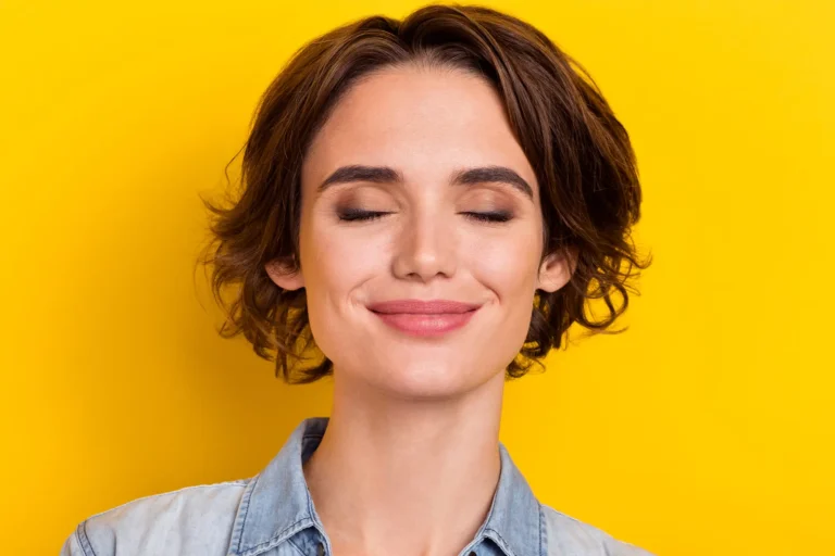 Smiling woman with closed eyes against bright yellow background