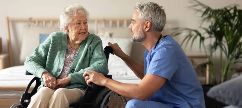 Care worker speaking with elderly woman in wheelchair