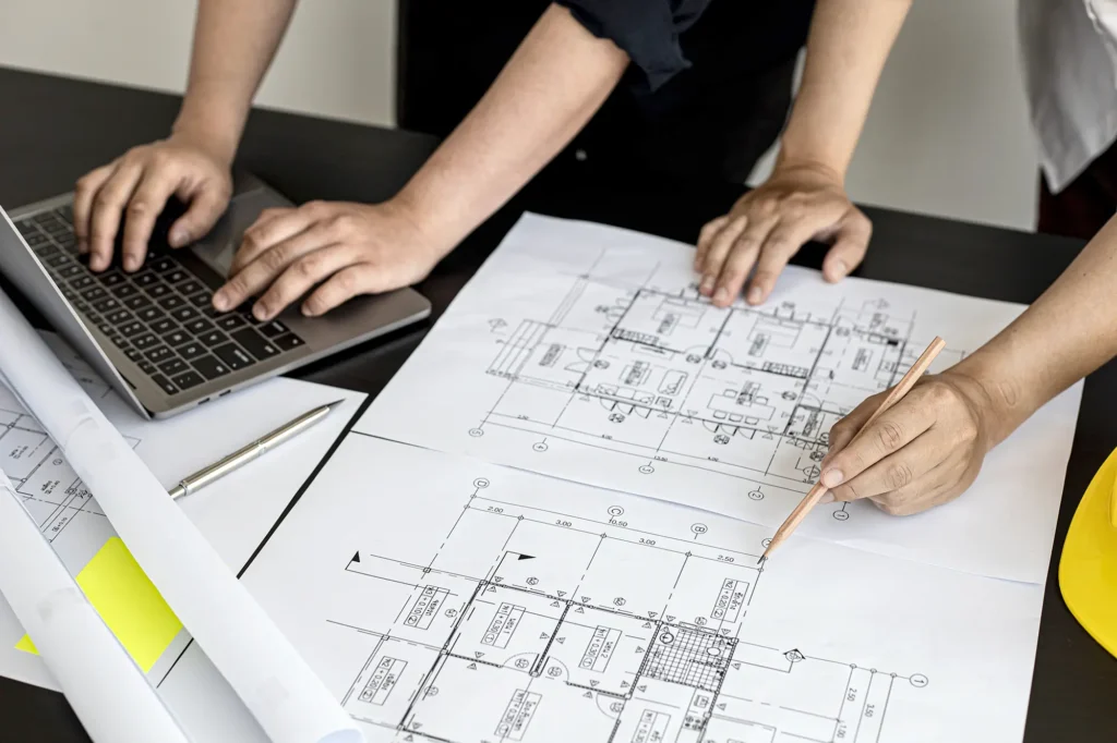 Architects reviewing building plans beside a laptop