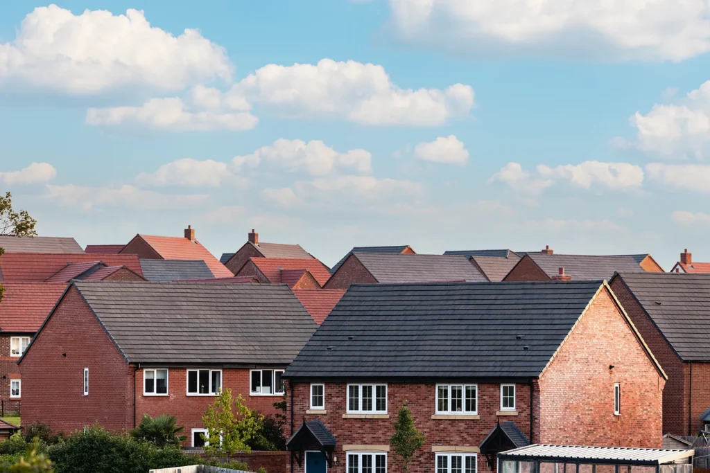 Brick suburban houses beneath a blue sky with clouds