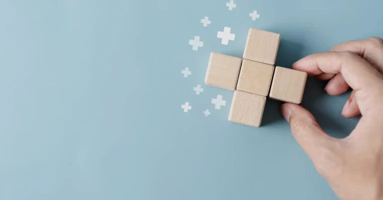Hand adding wooden block to cross, surrounded by plus signs