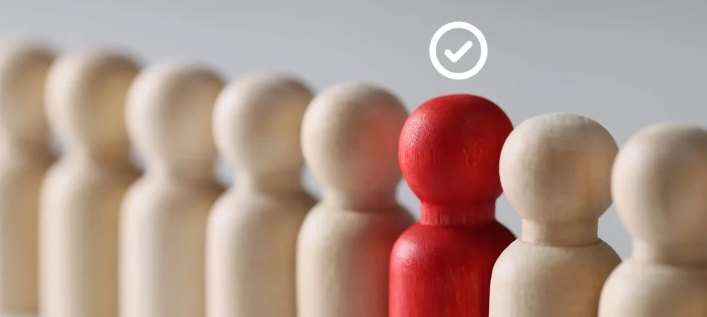 Red wooden figure selected among beige figures